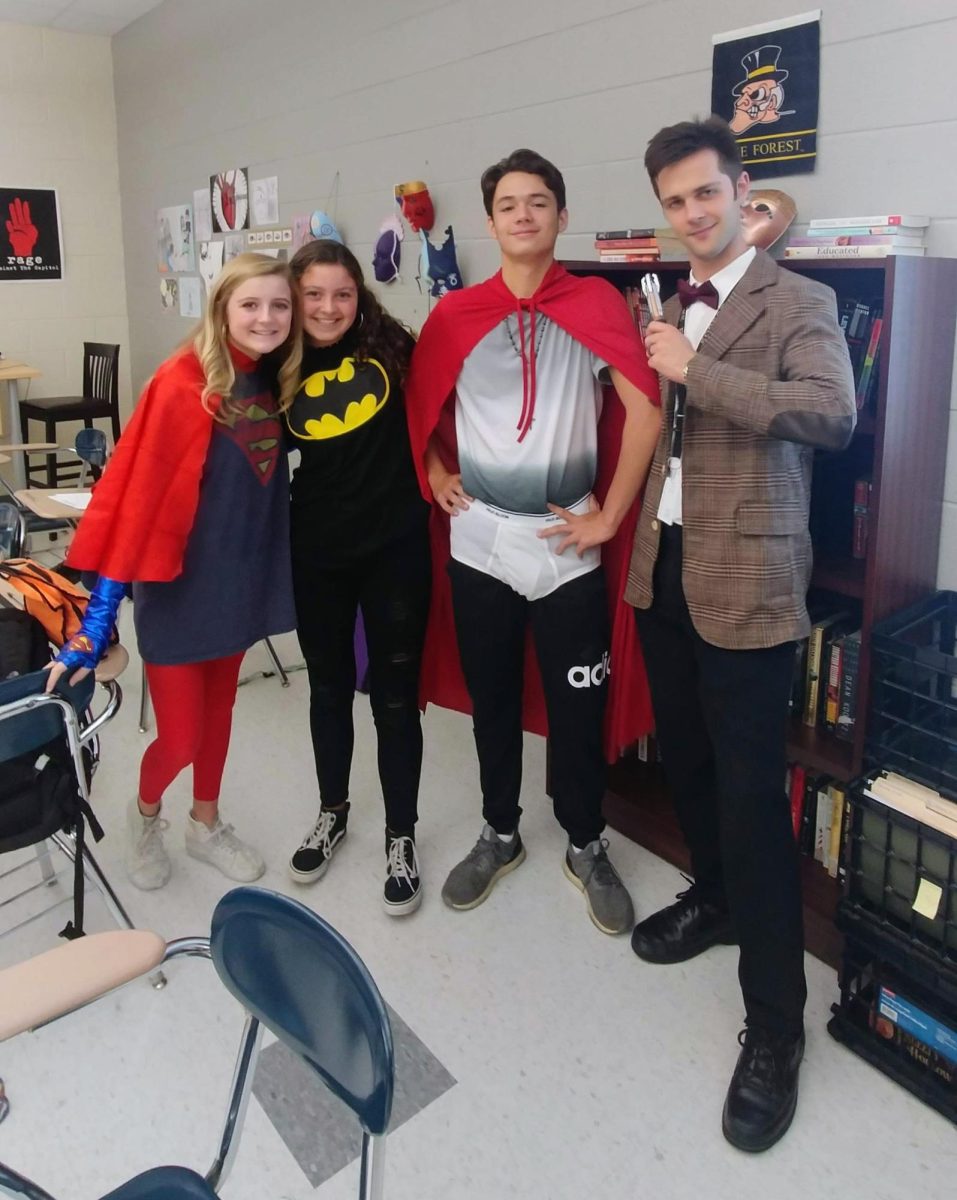 Sophomores Madi Kulis, Ava Rajacich, and Jordan Williams pose with English teacher Matt Barker on "Heroes and Villains" Day.