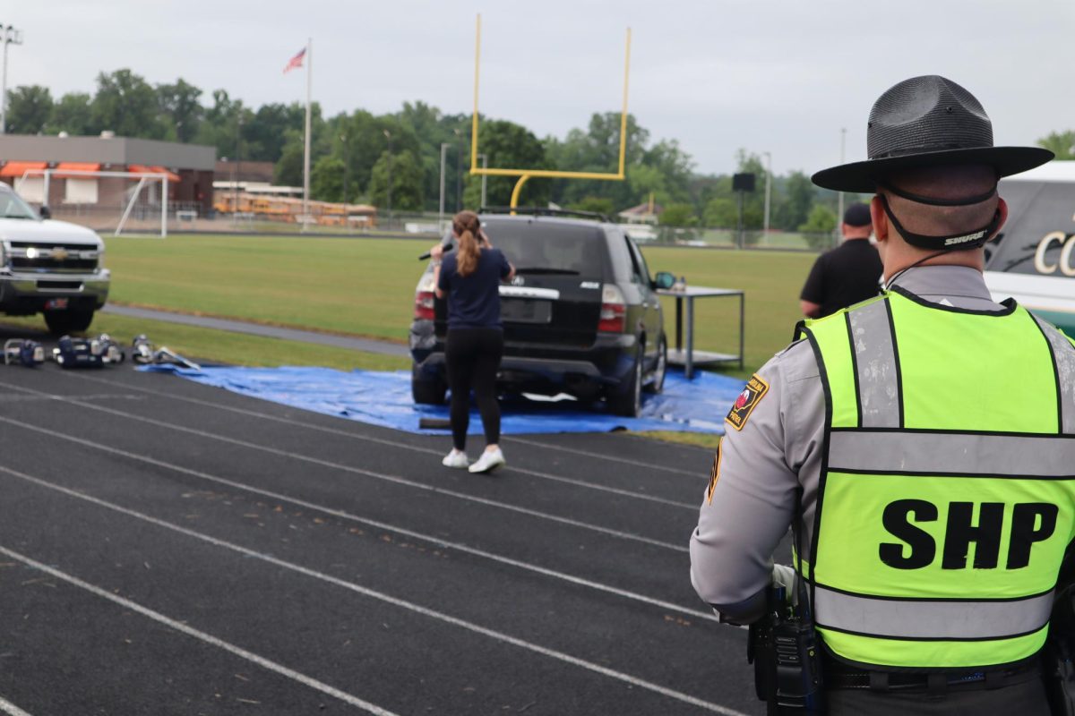 An officer looks on as a student approaches the scene of a wreck staged for the "prom promise" event held at Davie High School.