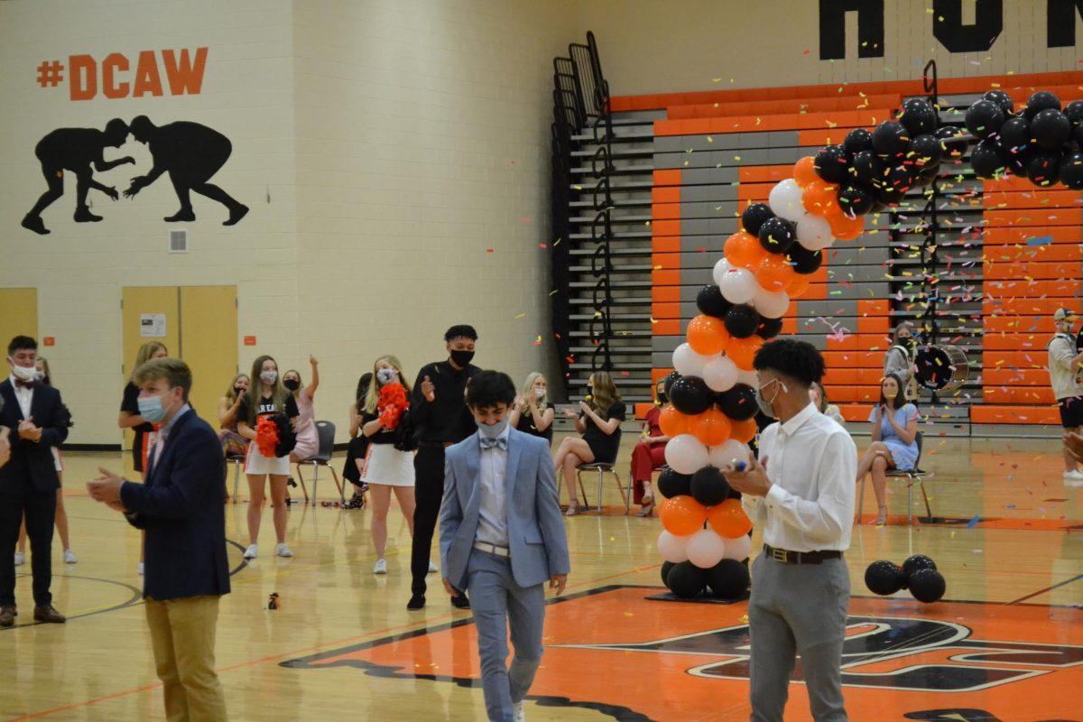 Confetti is released as Luke Stillson is declared Homecoming King. Runners-up Xander Youmans and Beaven Arey cheer him on.