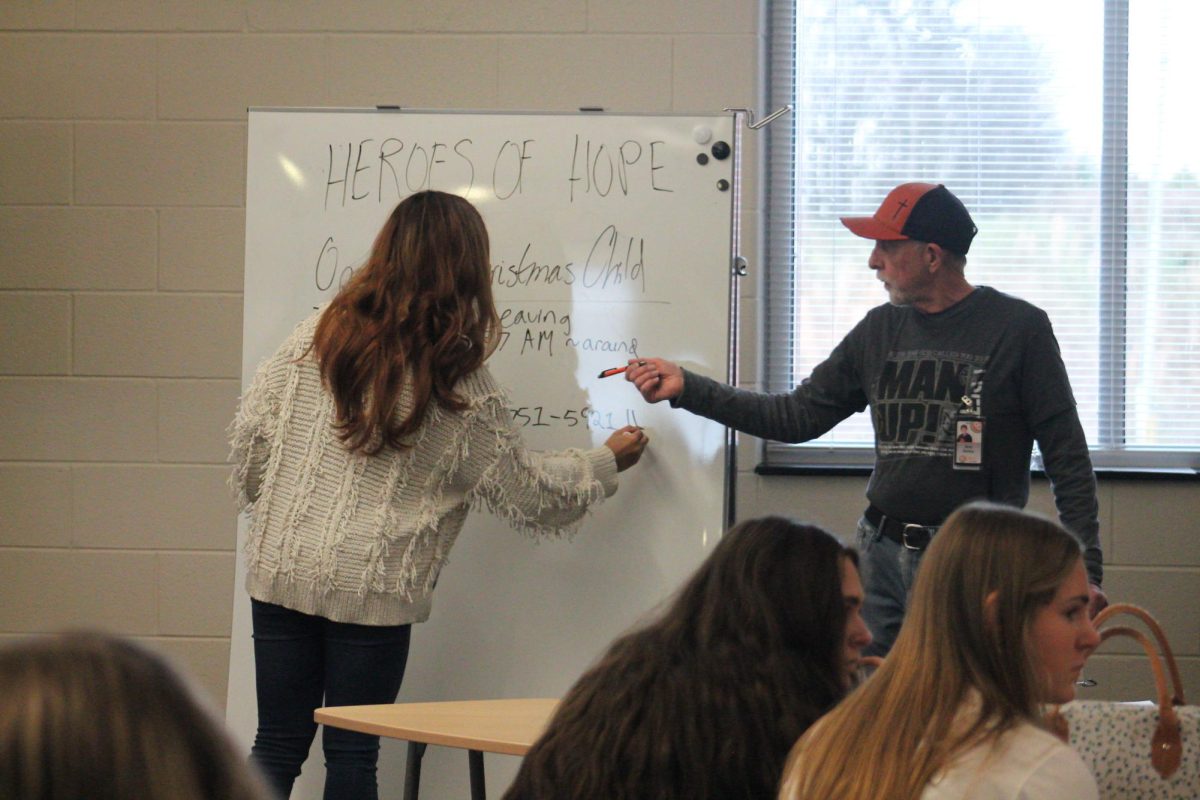 Club president Casey Cao and advisor Bob Bailey outline the plans for the Heroes of Hope club's participation in Operation Christmas Child during Flex on Monday, December 2.