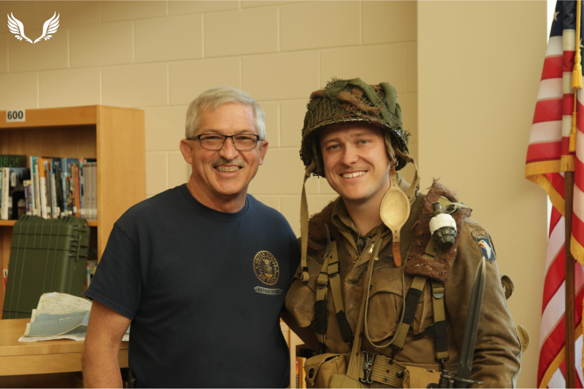 History teacher Zach Wood, dressed in paratrooper gear honoring a deceased veteran, poses with his father, Mark Wood, at the second annual Military History Museum.