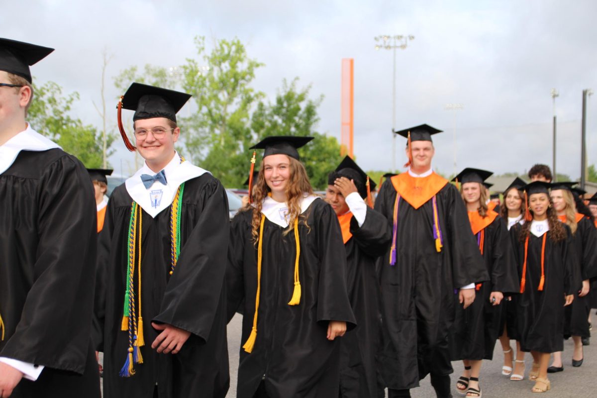 The Class of 2025 processes from the high school to the football stadium through a tunnel of cheering teachers as they prepare to graduate from Davie High School.