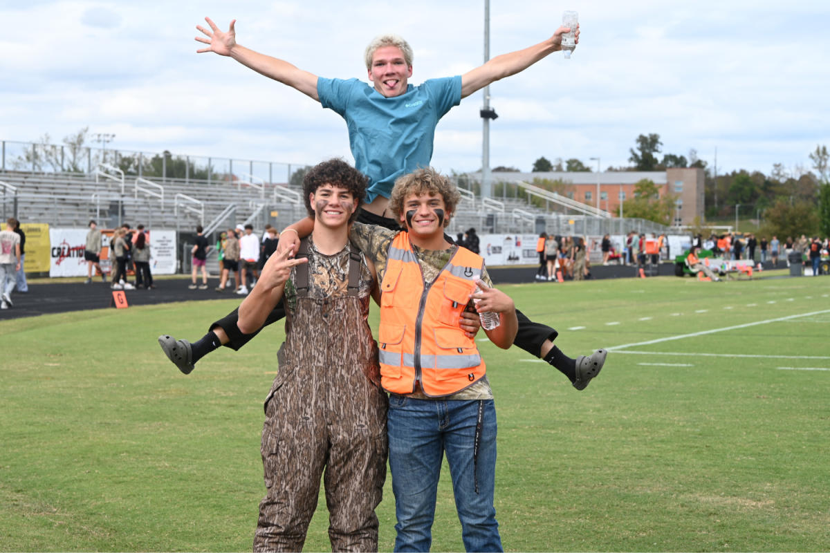 Juniors Carson Walker and Mason Boger pose for a picture while a student jumps behind them.