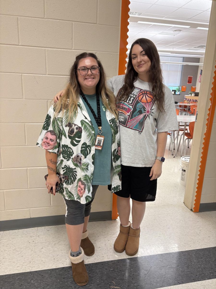 Teachers Kamryn Harris and Meranda Shoemaker pose in their sandler day fits, featuring their uggs and Harris’s shirt that has her fiancee's and dog's faces on it. 