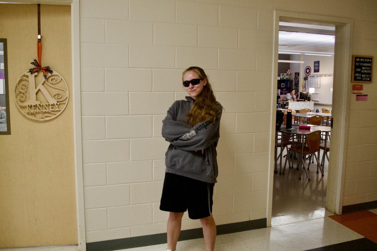 Senior Abby Clairmont stands posing in her baggy sweatshirt and shorts, sporting a pair of sunglasses.