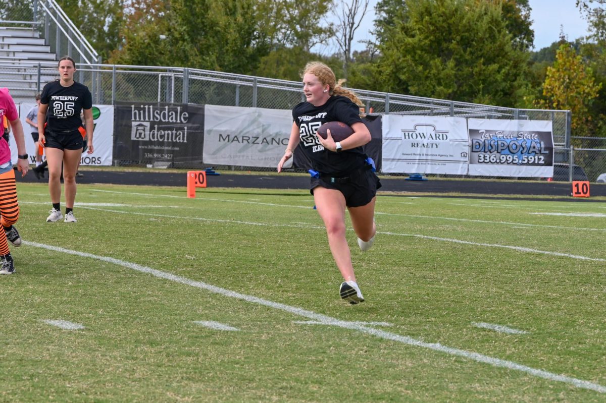 The quarterback for the Powder Puff football team runs down the field.