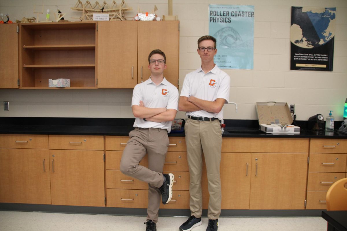 Seniors Carter Spillman and Bryson Lantz stand in their classroom leaning against the cabinets in their polo shirts and khaki pants.