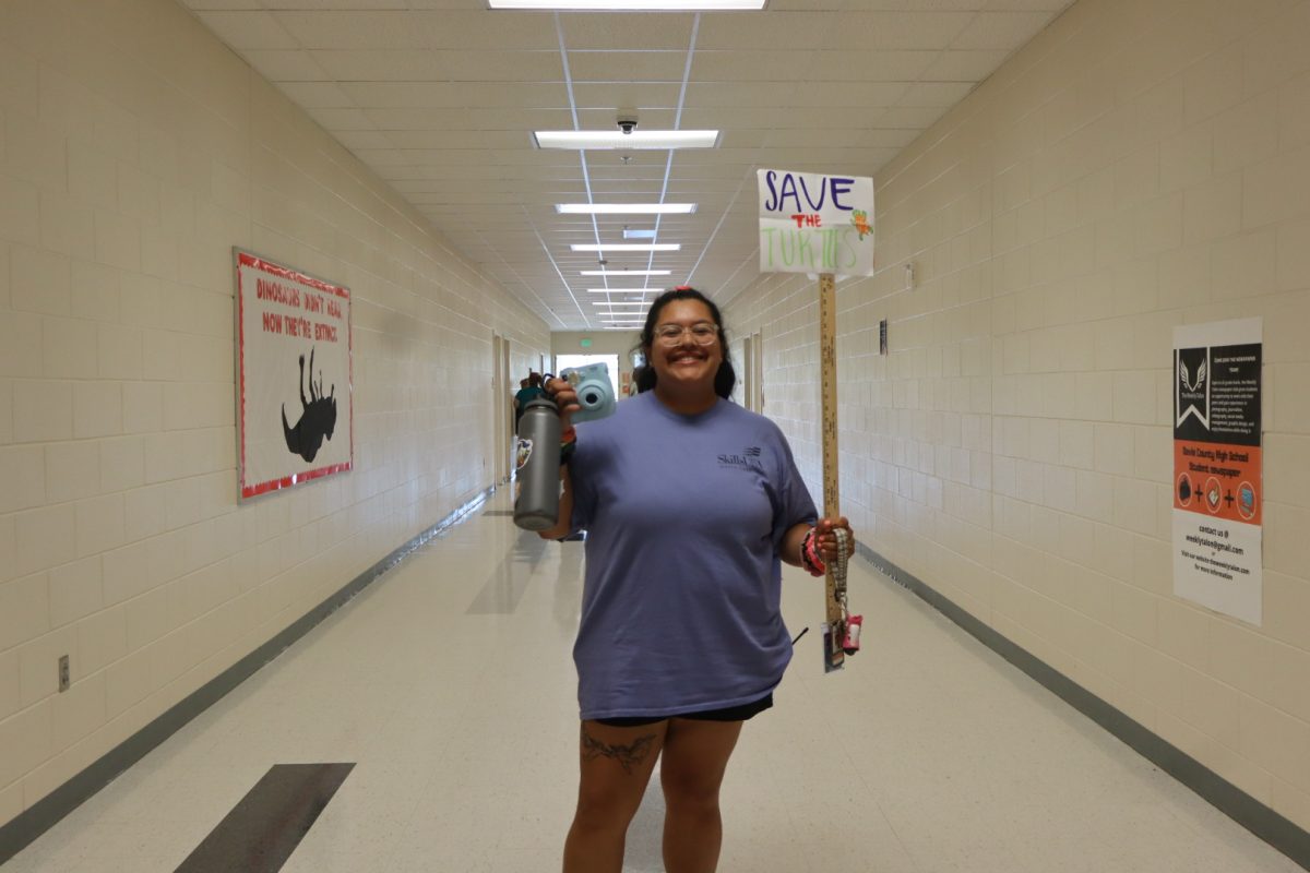 Office Staff Jackie Gonzales is dressed in her best 2019-era VSCO girl costume. Sporting scrunchies, a save the turtles sign, metal water bottle, and a polaroid camera added to her whole outfit.