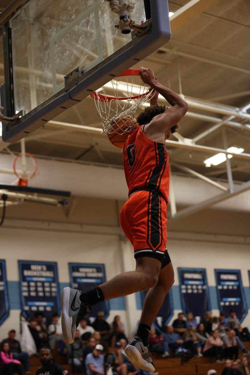 Dunking the ball into the hoop, sophomore Noah Dulin holds the rim as the ball drops to the floor.