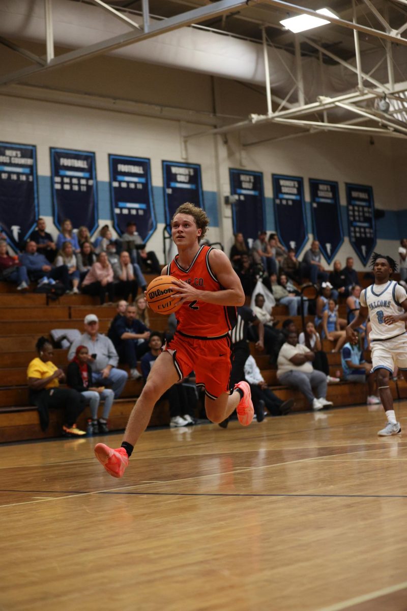 Preparing for the shot, senior Ethan Driver drives up the court ready to score.