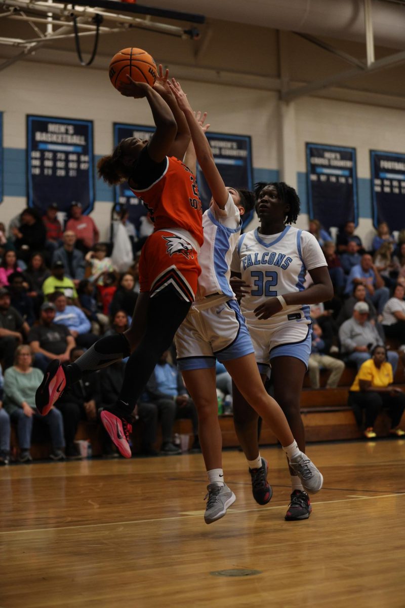 Facing the defense, Senior Makenzie Gentry jumps to make the layup and break the tie with the Falcons.