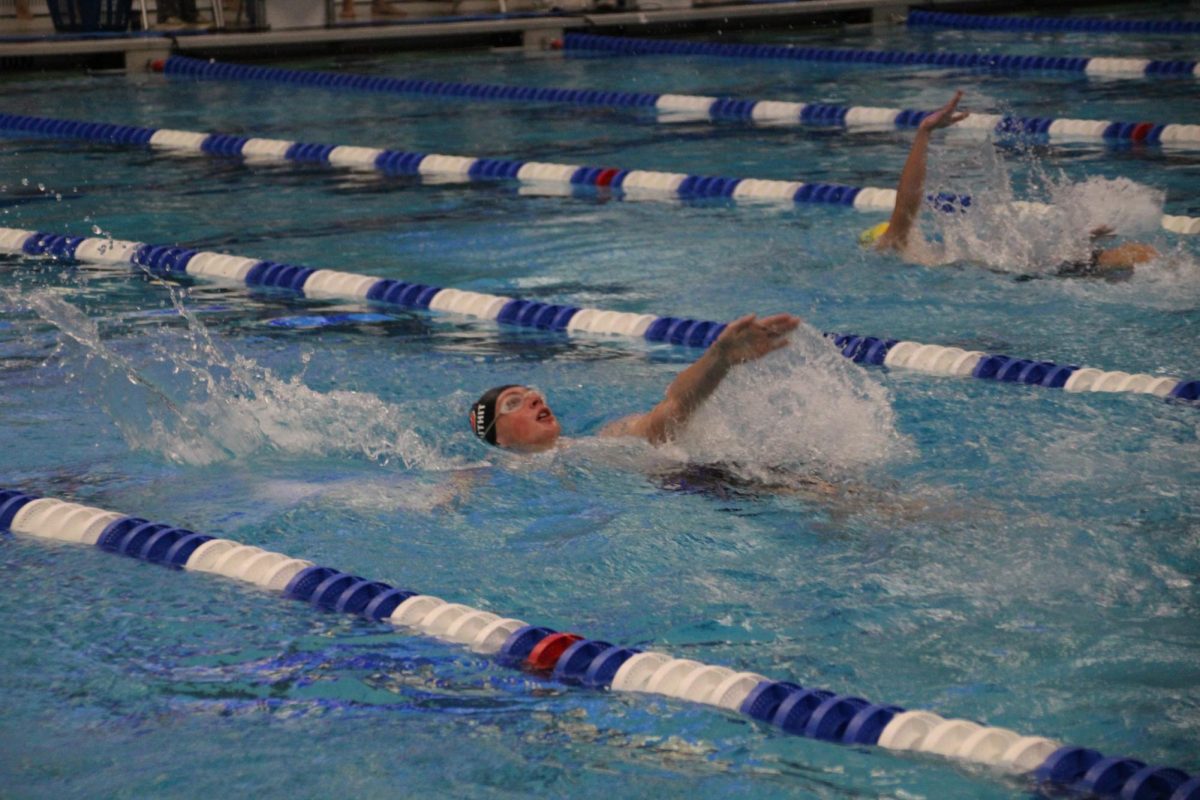 Freshman Lucas Douthit pulls his way through the 100 backstroke racing the competitors beside him. 