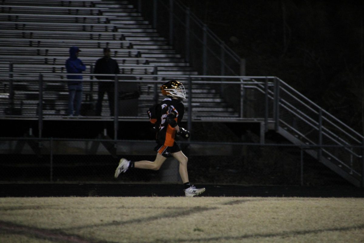 Grayson Daugherty sprints down the field trying to out run his defenders, making a lane for hum to go to goal. 