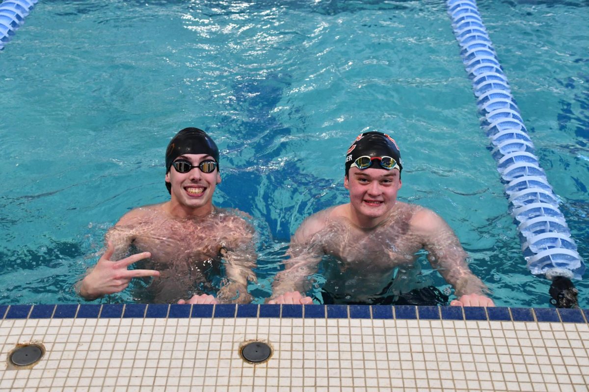 Senior Luke Wollner and Junior Ethan Diemer smile for the camera on the wall during the mid-meet break.