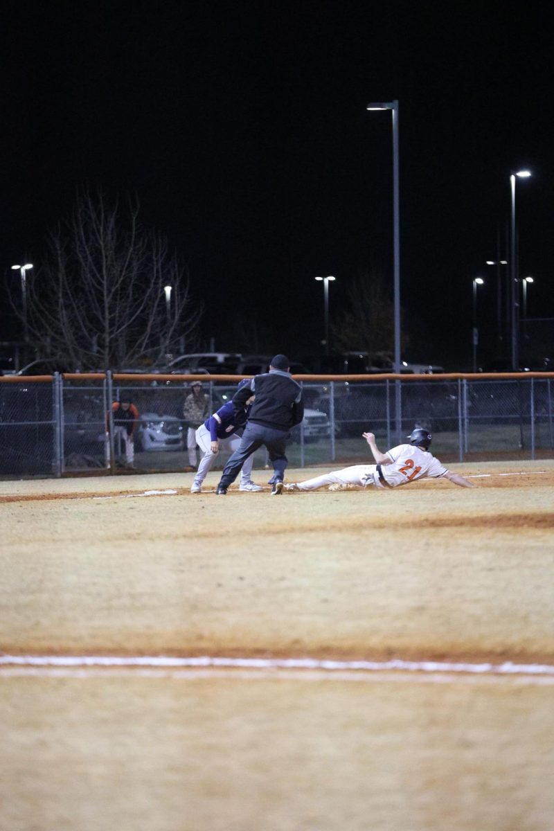 Junior Blake French slides into the plate, attempting to make it before he gets out. 
