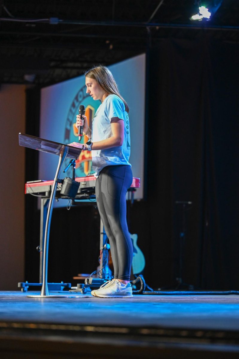 Carrington Pitcher speaks on the stage about how Christ has affected her life. 