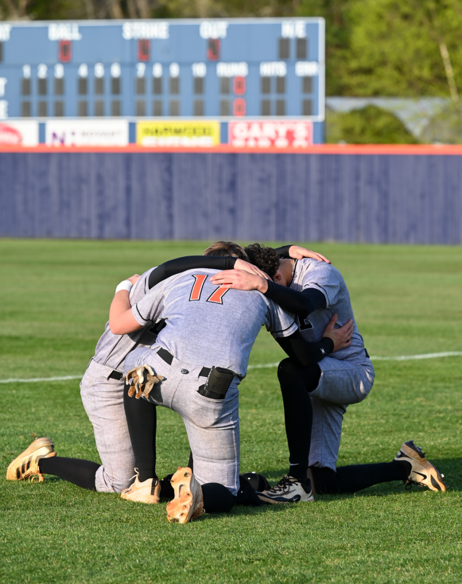 Ty Sain, Hayden Potts, and Tanner Steinour pray before the game starts.