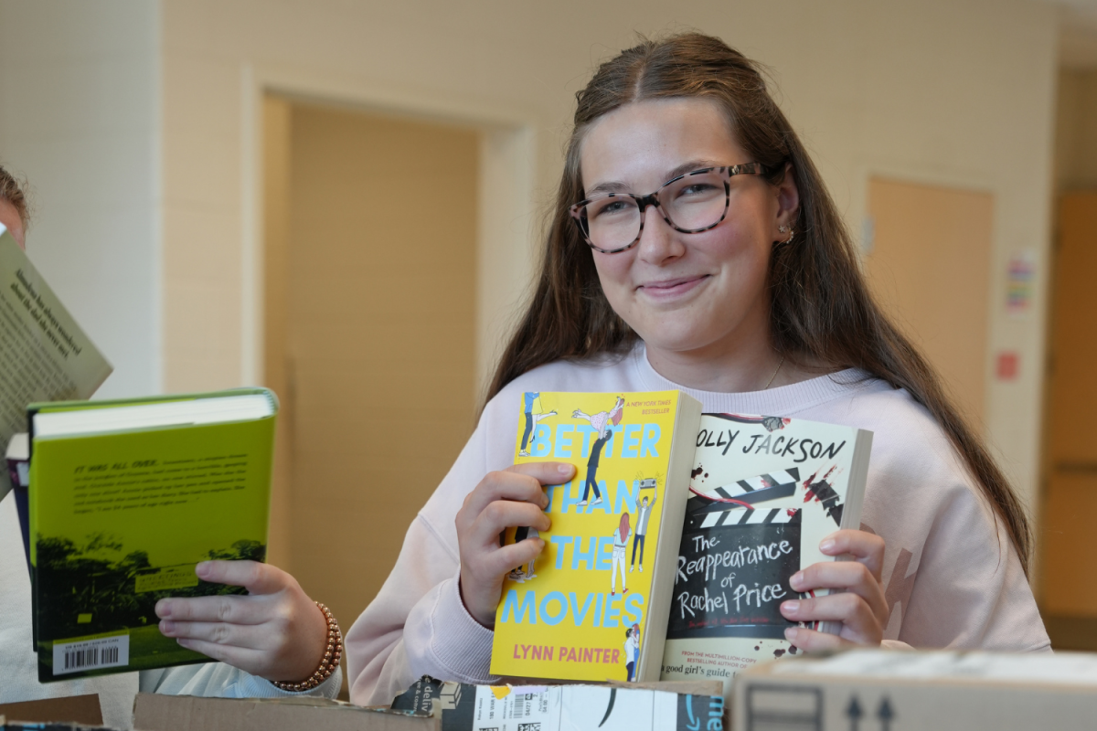 Junior Evie Conlin shows off copies of two books donated to Davie High's Battle of the Books Club. After the club's Amazon wish list was reposted by a TikTok account with over one million followers, the club was flooded with donations.