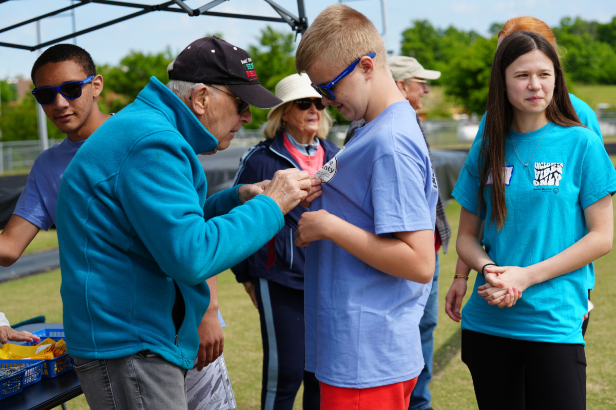 Volunteers at the awards tent pin ribbons on to the athletes while congratulating them on their stellar performances. 