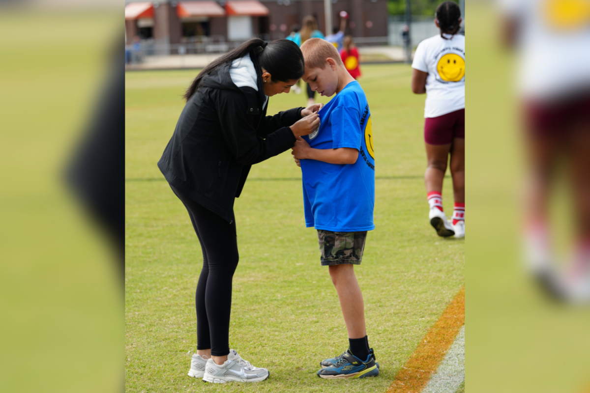 Keylin Andrade pins her buddies ribbon on his shirt after he raced. Congratulating him on his stellar performance, and giving encouragement before the next race.