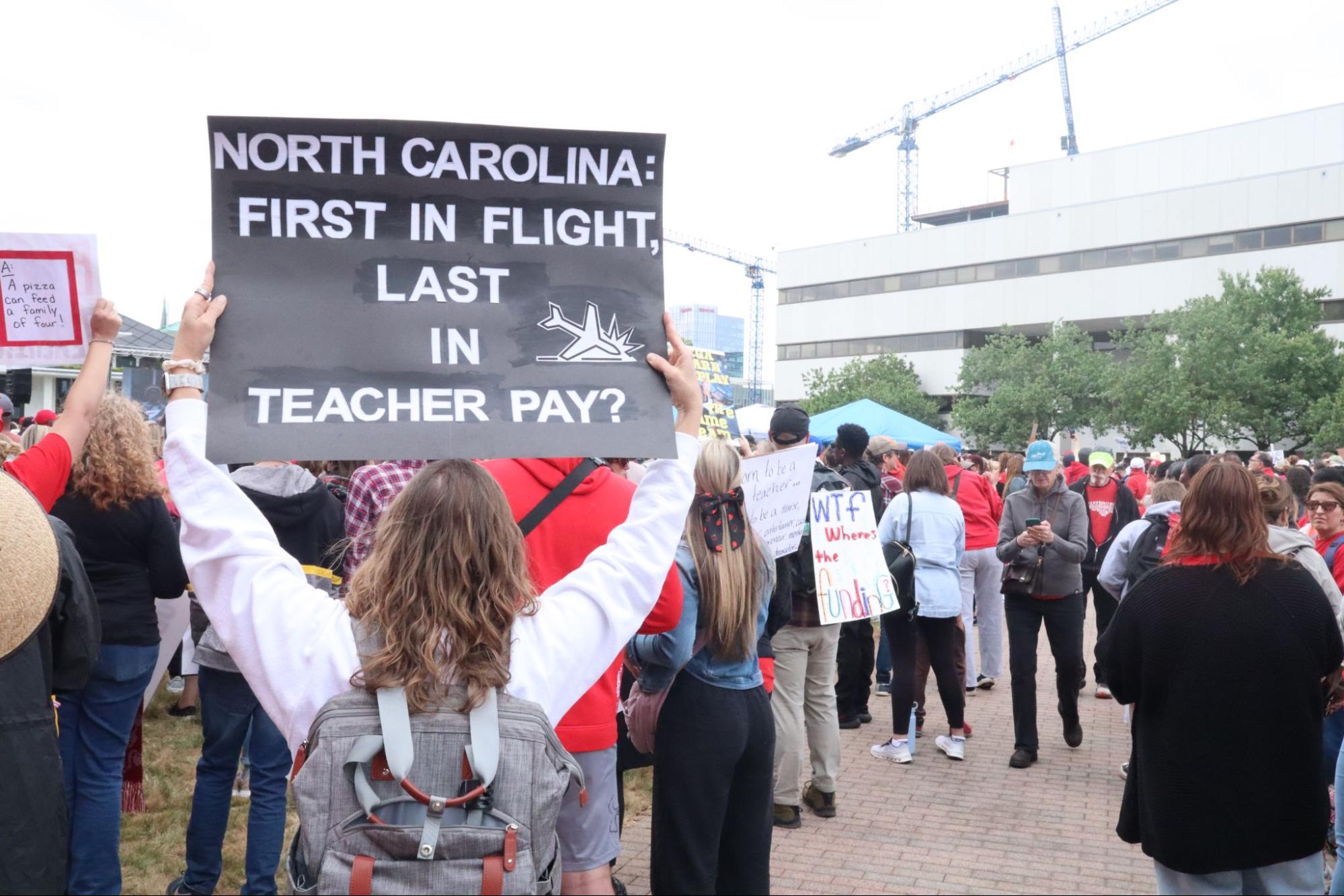 A protester stands on Halifax Mall holding a sign that says "North Carolina: First in Flight. Last in Teacher Pay?" Currently, North Carolina ranks 50th in the country in per-pupil spending. | Photo courtesy Matt Barker