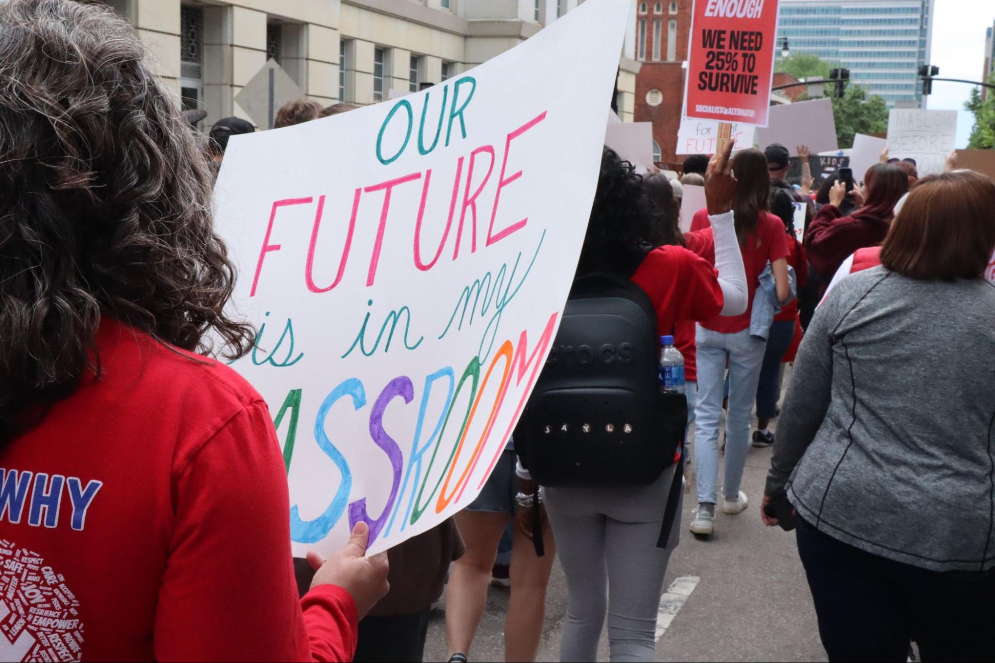 A protester carries a sign saying "Our future is in my classroom" as she and fellow supporters march around the North Carolina General Assembly. | Photo courtesy Matt Barker