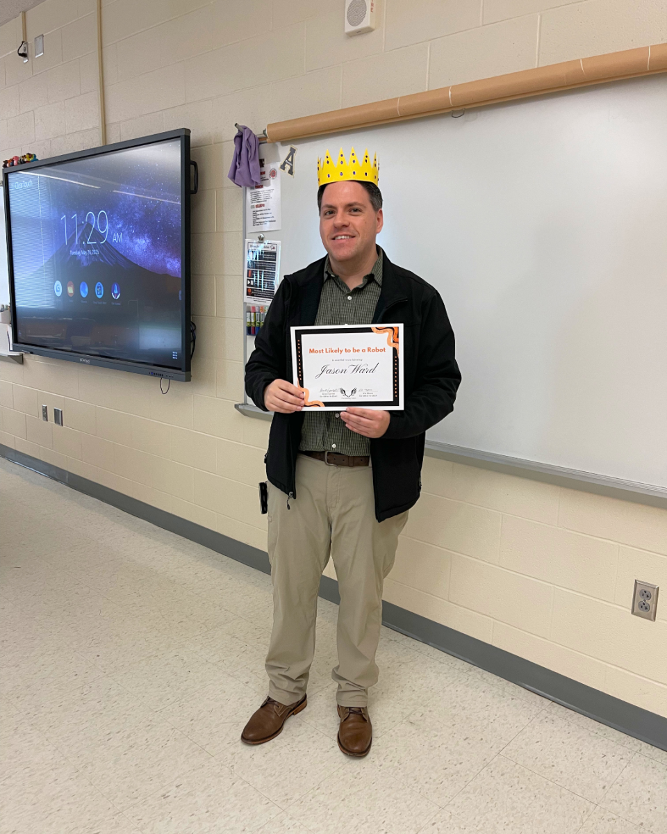 Striking a convincing, human-like pose, Jason Ward stands in his classroom with his Student Choice Award in hand.